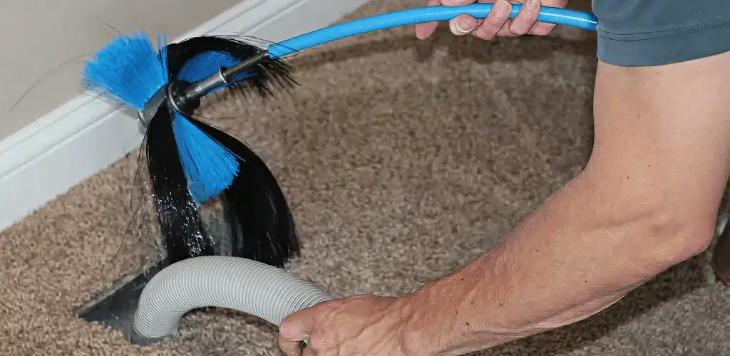 Dryer vent cleaning technician brushing lint from a vent line in Baton Rouge, LA