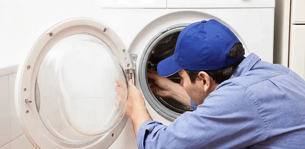 Washing machine repair handyman inspecting a front-load washer drum in Baton Rouge, LA