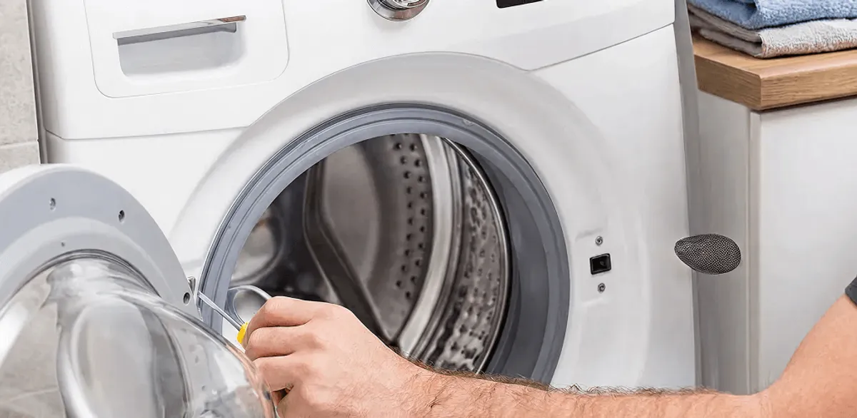 Handyman repairing a front-load washing machine and inspecting the drum in Baton Rouge, LA
