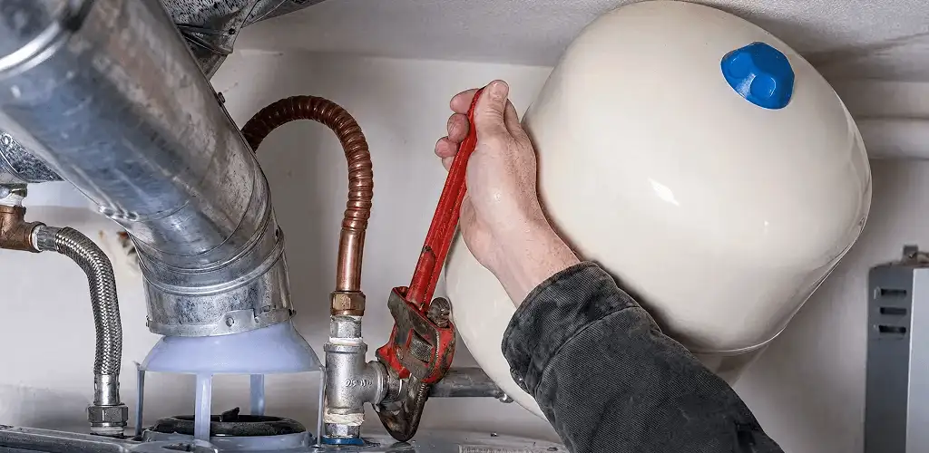 Water heater repair technician tightening plumbing connections near a tank unit in Baton Rouge, LA