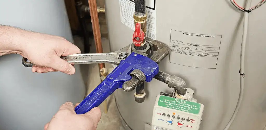 Water heater repair technician tightening the shutoff valve and supply line in Baton Rouge, LA
